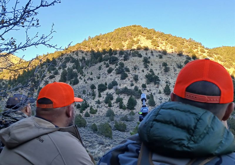 Hunters glassing a hillside behind a spotting scope