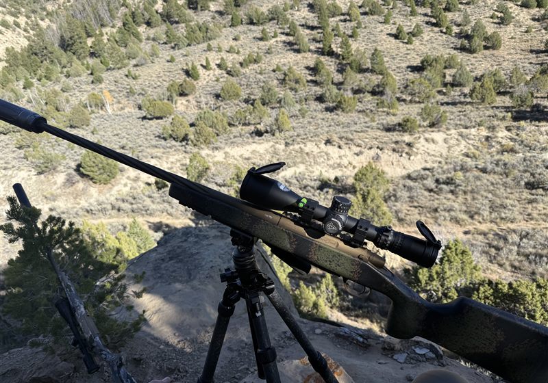 Bolt rifle set up on a tripod overlooking a canyon