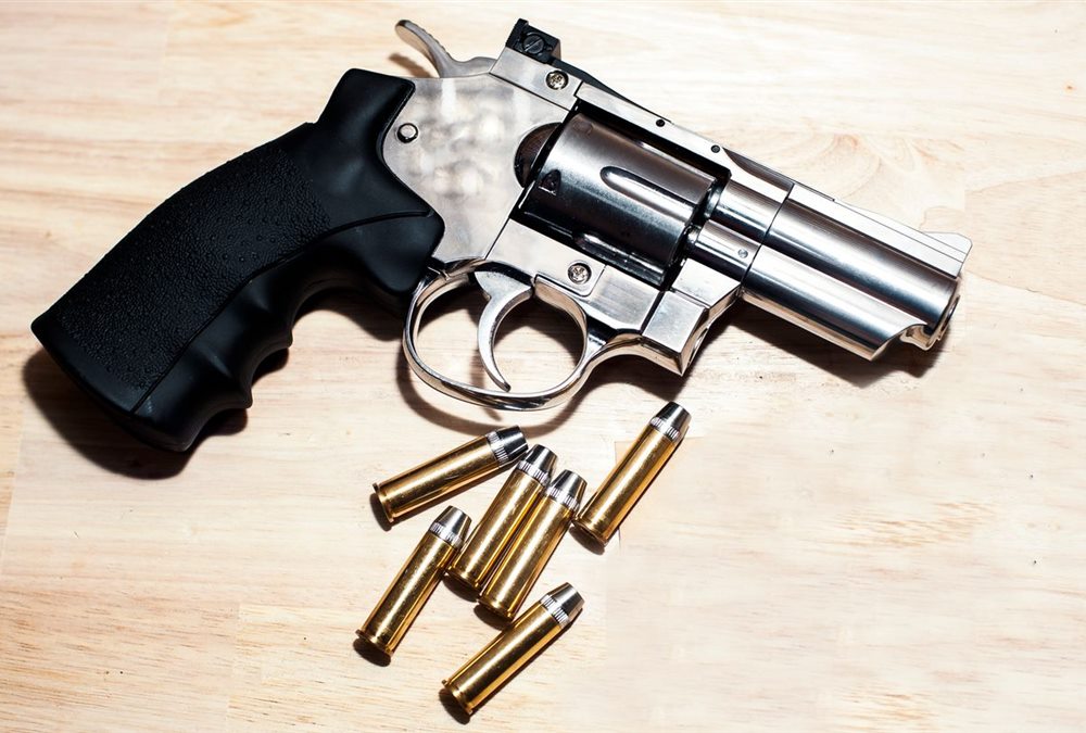 A stainless revolver with cartridges on a wood counter